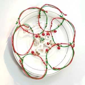 Macro view of woven Christmas bracelets with Santa and snowflake charms in a ceramic dish