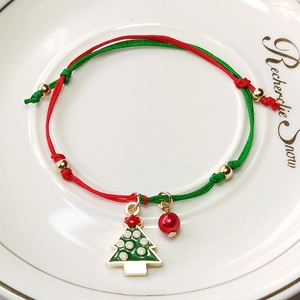 Detail of Christmas tree charm and red bead on festive green and red braided bracelet