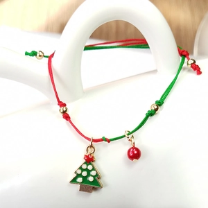 Macro view of adjustable red and green Christmas tree woven bracelet with gold charms