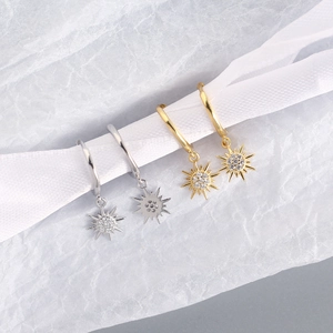Detail shot of sun-shaped earrings in gold and silver finish with sparkling gemstones