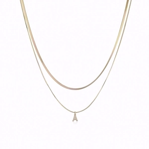 Detail of double-layer gold snake chain featuring a micro-paved letter A pendant