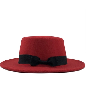 Détail d'un chapeau en feutre de laine rouge foncé avec ruban noir et décoration de nœud