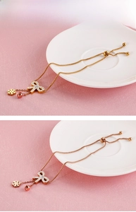 Detail of adjustable gold steel bracelet with zircon butterfly and snowflake charms