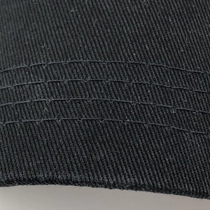 Close-up of durable reinforced stitching on black cotton baseball cap brim with dense seams