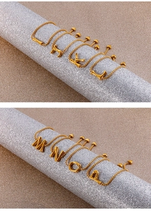 Close-up of golden alphabet snake chain bracelets with adjustable heart charm slider