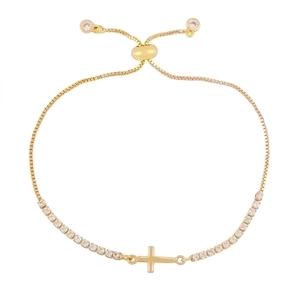 Bracelet croix doré ajustable orné de zircons brillants sur un fond blanc épuré