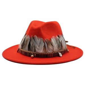 Dettaglio cappello in feltro rosso con piume naturali e rifiniture di perline boho