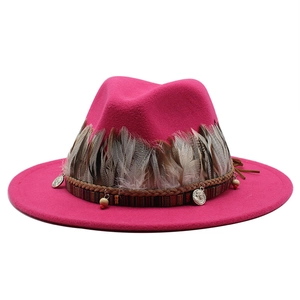 Dettaglio del cappello fedora in lana magenta con fascia etnica, piume e ciondoli in metallo