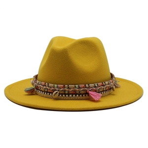 Detail of yellow wool fedora hat featuring bohemian tassels and sea shell decor