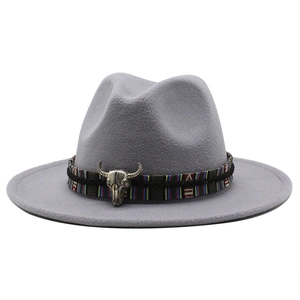 Detail of light gray wide brim fedora with ethnic woven band and silver bull head badge