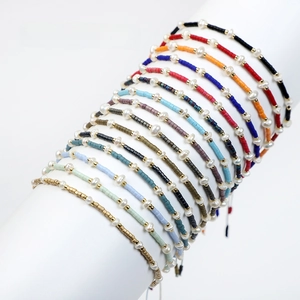 Macro view of fifteen multicolored handmade beaded bracelets with freshwater pearls and gold beads