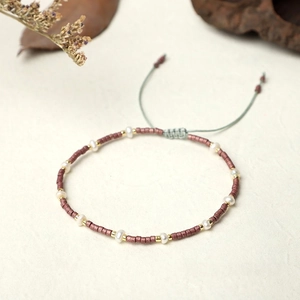 Macro shot of handmade Miyuki bead bracelet with freshwater pearls and green cord