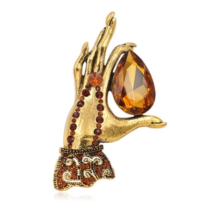 Macro shot of vintage gold hand-shaped brooch with amber teardrop gemstone and crystals