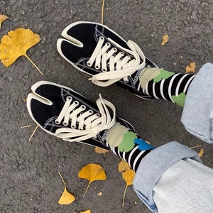 Japanese style black tabi sneakers with colorful patterned socks on ginkgo leaf ground