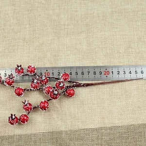 Detailed view of artificial red berries with snow finish on beige linen background