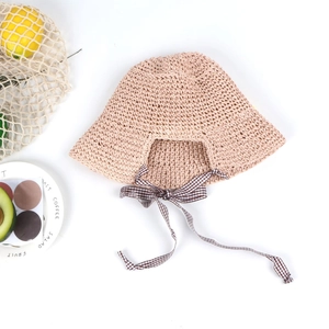 Close-up of crochet straw sun hat featuring woven texture and a brown checkered bow
