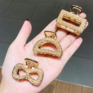 Three-piece set of geometric gold hair clips including bow and rectangle shapes