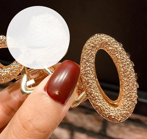 Detailed close-up of golden alloy hair claw featuring intricate 3D embossed rose textures