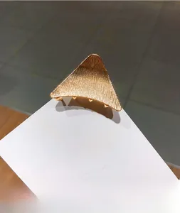 Detailed view of golden triangular hair claw clip with vertical texture on metal surface