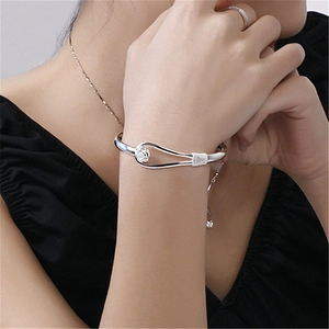 Close-up of silver rose bracelet with woven texture and floral details on a model