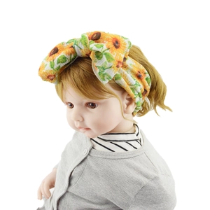 Detail of baby headband with sunflower print and large bow on model head