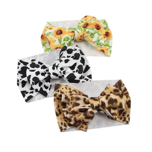 Baby headbands with large bows in sunflower, cow, and leopard prints on soft fabric