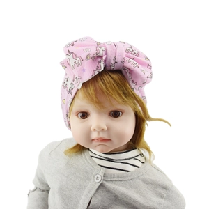 Close-up of pink baby headband with cartoon unicorn prints and a large fabric bow
