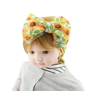 Detail of infant headband featuring a large sunflower print bow on soft fabric material