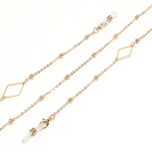 Detail of golden geometric eyewear chain with diamond charms and lobster clasps