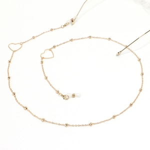 Detail of gold glasses chain featuring delicate beads and heart-shaped charms