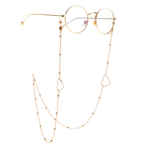 Detail of a golden eyewear chain with heart pendants and beads on round frame glasses