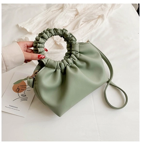 Detail of light green pleated handbag with round ruffled handle and gold metal hardware