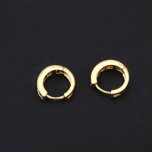 Detail of 18K gold-plated minimalist hoop earrings on a black leather background