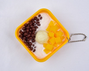 Close-up of artificial dessert keychain with red beans and mango cubes in a yellow box