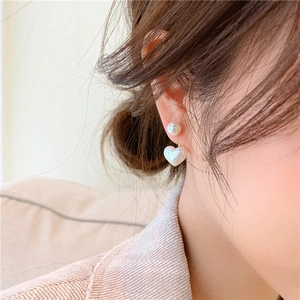 Dettaglio di eleganti orecchini di perle a cuore indossati per un look di lusso