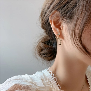 Detailed view of layered gold butterfly earrings with sparkling crystals on a model
