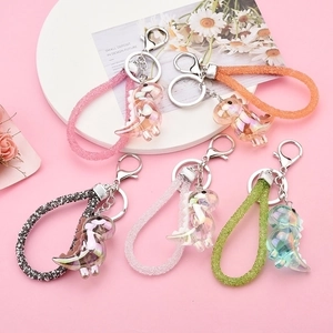 Fünfer-Set bunte Dinosaurier-Schlüsselanhänger aus Acryl mit Glitzerbändern auf Rosa