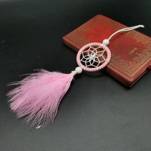 Pink dreamcatcher pendant with delicate feathers and white beads on vintage background