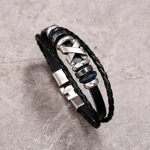 Macro detail of multilayer black braided leather bracelet with vintage silver X-stud accents