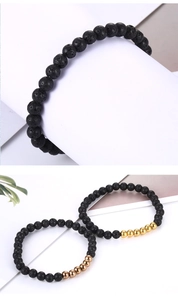 Close-up of black lava stone bead bracelet with polished metal accents and porous texture