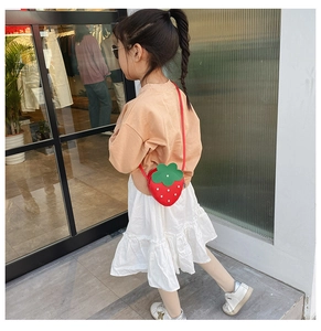 Detailed view of child wearing a strawberry crossbody bag with rhinestones
