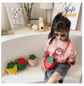 Detail view of strawberry-shaped kids bags with shiny studs and colorful leather finish