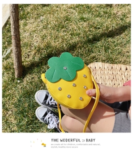 Detail of yellow strawberry bag with sparkly rhinestones and green leaf design