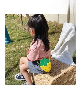Detail showing the strawberry-shaped kid handbag with silver studs and green leaves