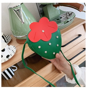 Detail of creative strawberry crossbody bag with rhinestones held in a lifestyle setting