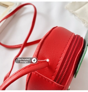 Detail of red strawberry bag showing leather texture, stitching, and strap attachment