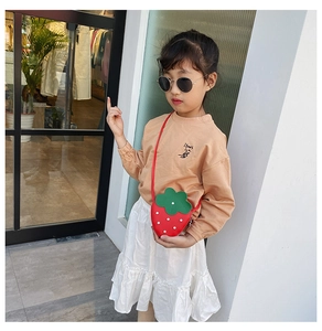 Close-up of strawberry-shaped child crossbody bag with vivid red PU leather and green leaf