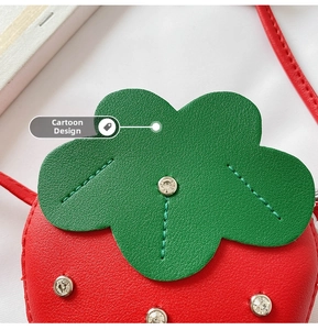 Detailed close-up of strawberry-shaped kids bag with rhinestones and faux leather texture