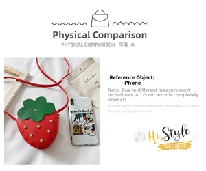 Mini strawberry crossbody bag size comparison with smartphone on white fabric background