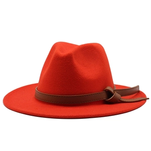 Detail view of red felt fedora hat featuring a brown faux leather decorative band